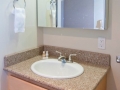 Bathroom vanity with wood cabinet, oval sink, granite countertop, and mirrored medicine cabinet