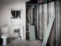 Bathroom under renovation with toilet, exposed wall framing, pipes, and unfinished shower area