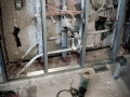 Exposed bathroom wall framing with plumbing, wiring, and drainpipes during renovation