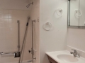 Bathroom with tiled tub and shower, white sink, wood vanity, and mirrored cabinet