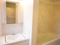 Bathroom with white sink, mirrored cabinet, and bathtub with beige marble-patterned surround