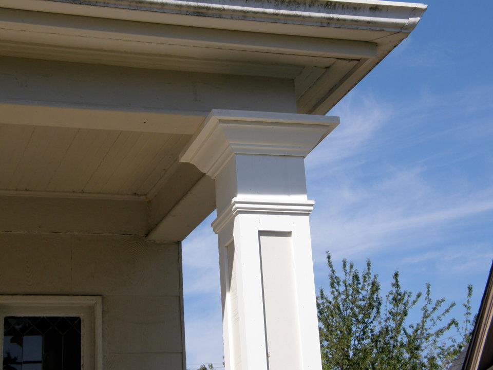 White decorative porch column with layered trim supporting a gray roof overhang