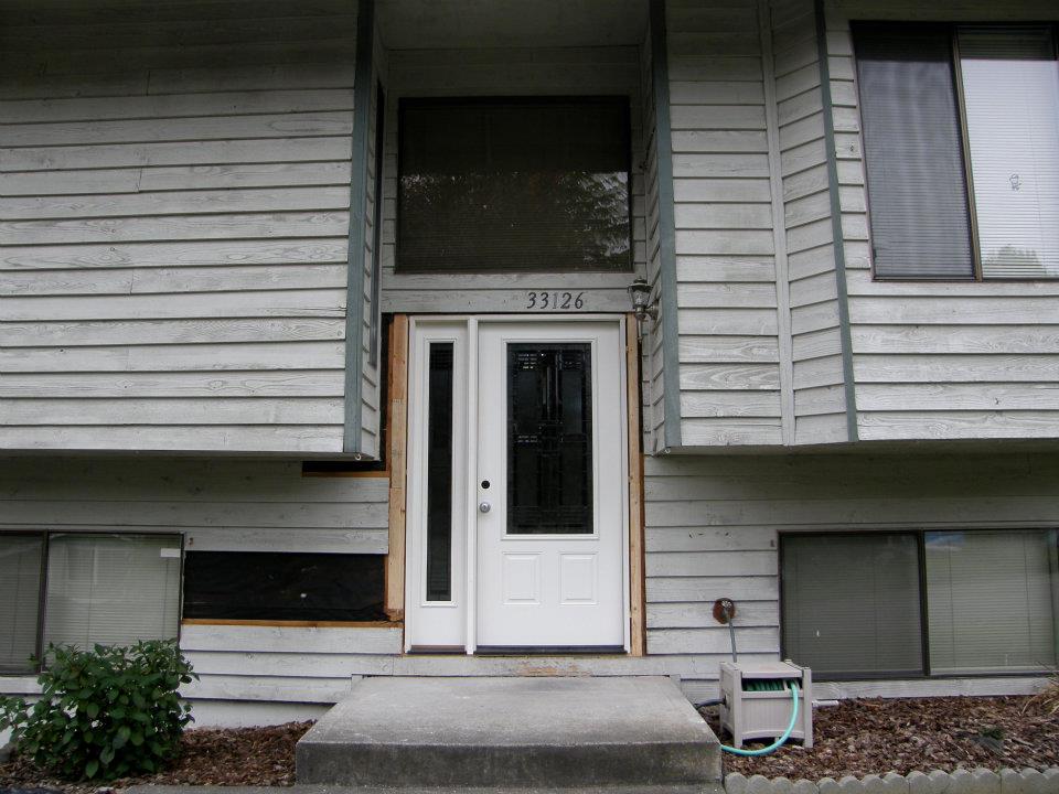 White front door with decorative glass and sidelight on a gray-sided home