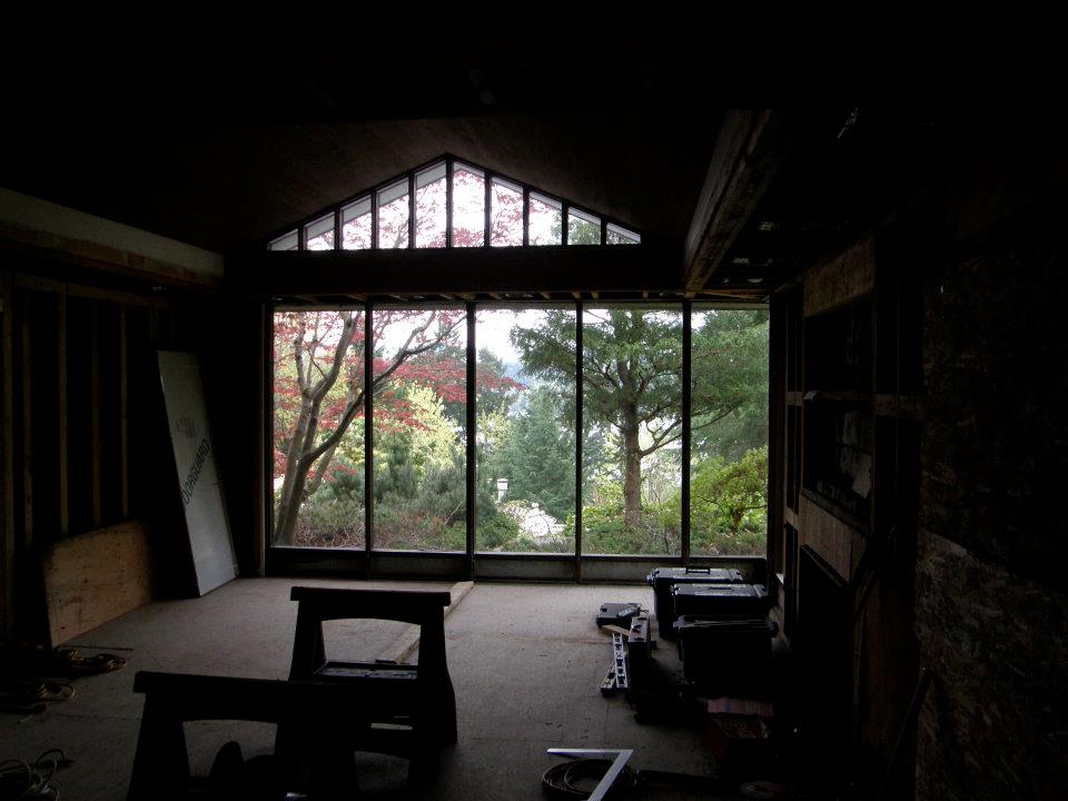 Unfinished room with floor-to-ceiling windows and triangular windows overlooking trees