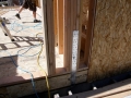Exposed wall framing with metal connector, plywood sheathing, and construction tools