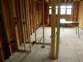 Unfinished interior with exposed wood wall framing, wiring, windows, and plywood floor