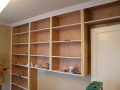 Built-in wood shelving under construction with open shelves and painting supplies