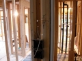 Exposed wood wall framing with black plumbing pipes and electrical wiring