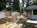 Home addition under construction with exposed framing, lumber, ladders, and building materials