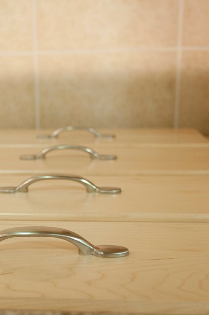 Close-up of light wood cabinet drawers with curved silver handles