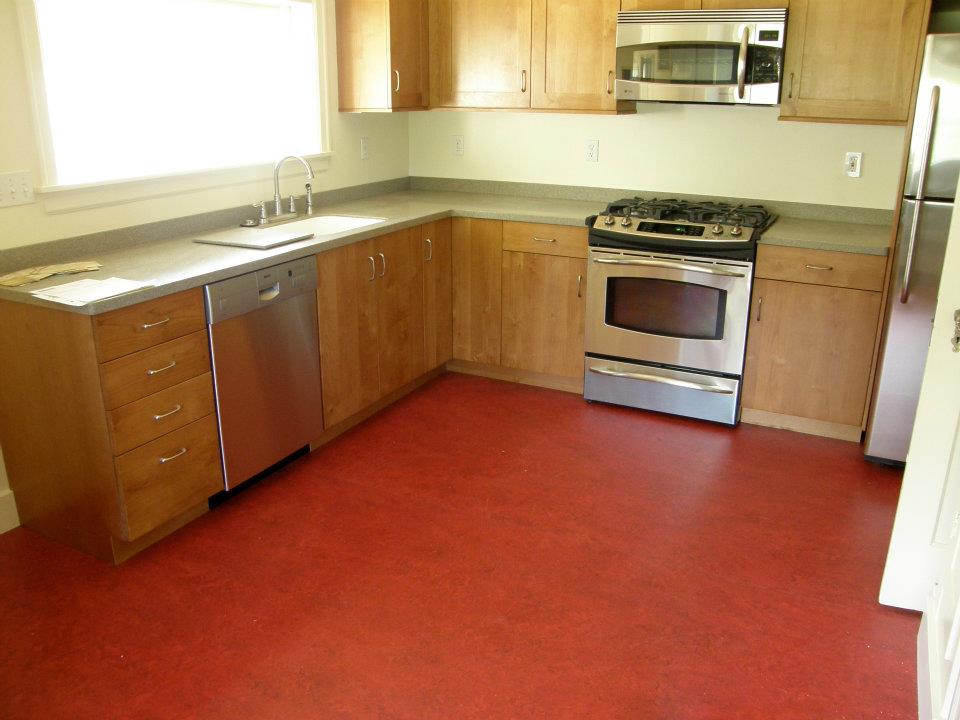 Kitchen with wood cabinets, stainless steel appliances, and red flooring