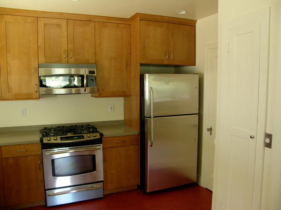 Wood kitchen cabinets with stainless steel range, microwave, and refrigerator