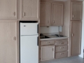 Compact kitchen with light wood cabinets, white refrigerator, sink, and two-burner cooktop
