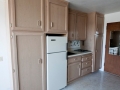 Compact kitchen with light wood cabinets, white refrigerator, sink, and cooktop