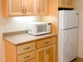 Light wood kitchen cabinets with white microwave and refrigerator