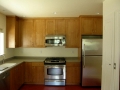 Wood kitchen cabinets with stainless steel range, microwave, and refrigerator