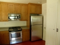 Wood kitchen cabinets with stainless steel range, microwave, and refrigerator