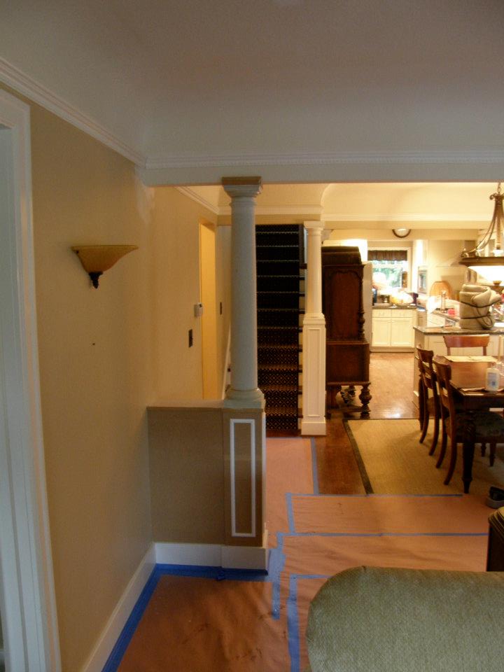 Interior hallway with decorative column leading to stairs, dining area, and kitchen