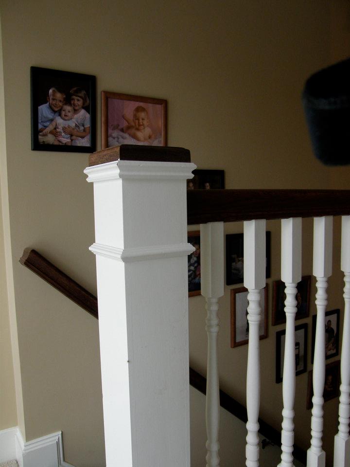 White stair railing with dark wood handrails and framed family photos on the wall