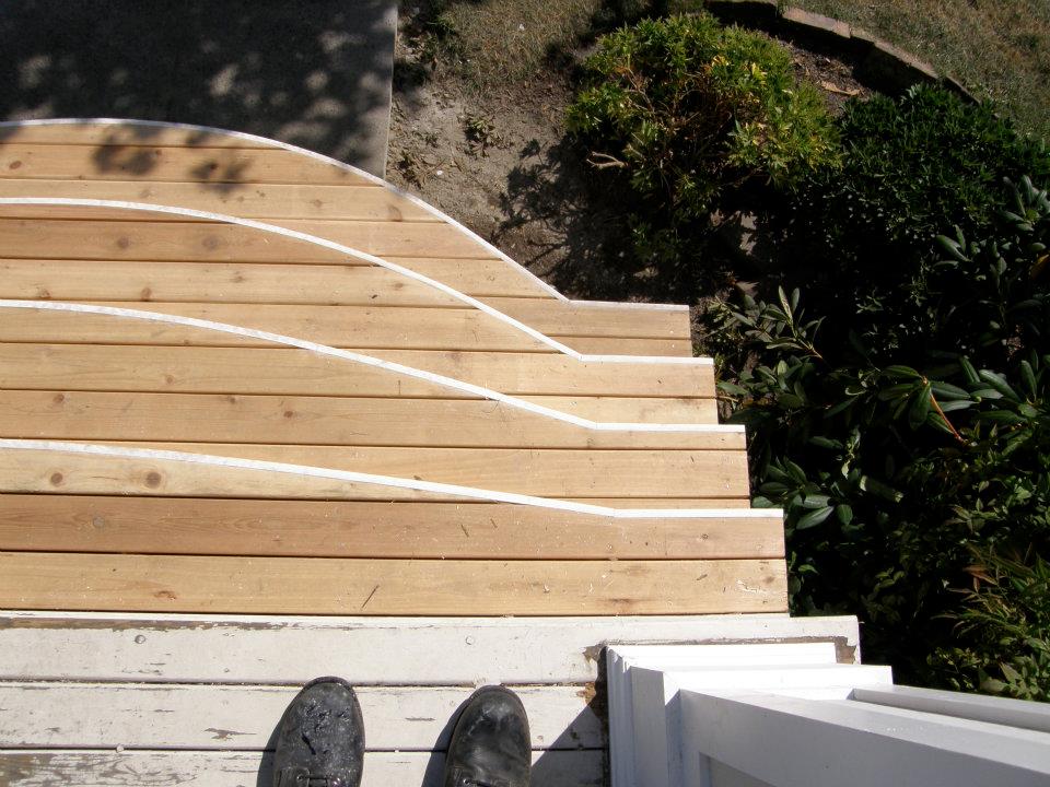 Curved unfinished wood porch steps with white trim viewed from above