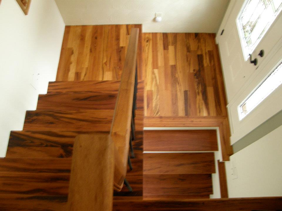Dark wood staircase with matching flooring and railing beside a white entry door