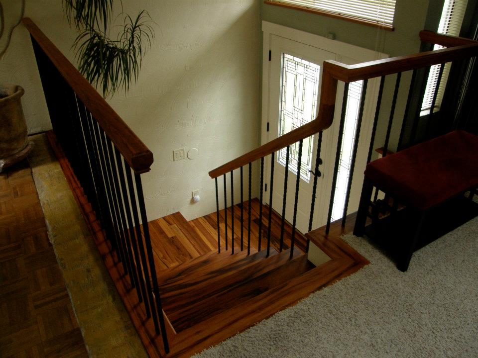 Wood staircase with dark railings leading down to a decorative glass front door
