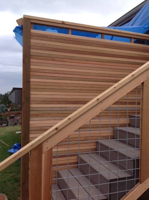 Outdoor wood staircase with cable railing beside a horizontal slat privacy wall