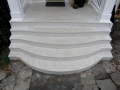 Curved white porch steps leading to a covered entry with white railings