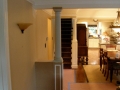 Interior hallway with decorative column leading to stairs, dining area, and kitchen