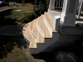 Curved wooden porch steps with white risers leading to a covered front porch