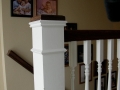 White stair railing with dark wood handrails and framed family photos on the wall
