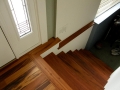 Dark wood staircase and handrail beside a white entry door with decorative glass