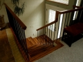 Wood staircase with dark railings leading down to a decorative glass front door