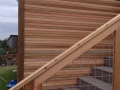 Outdoor wood staircase with cable railing beside a horizontal slat privacy wall