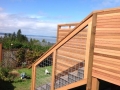 Outdoor wood staircase with wire railing and horizontal slat privacy wall